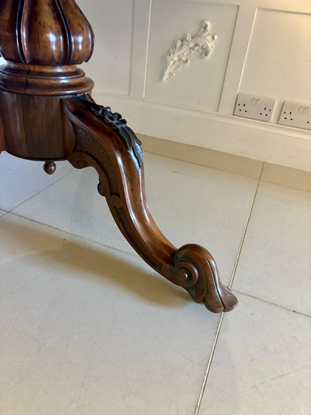 A Victorian circular rosewood dining table with a matched grain veneer top, shown tilted vertically on a carved pedestal base with scroll feet. View IX