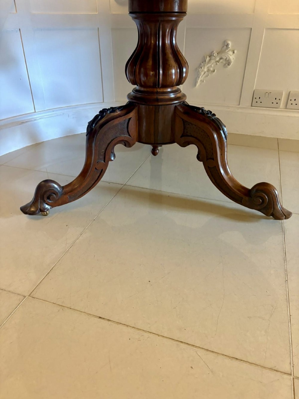 A Victorian circular rosewood dining table with a matched grain veneer top, shown tilted vertically on a carved pedestal base with scroll feet. View X