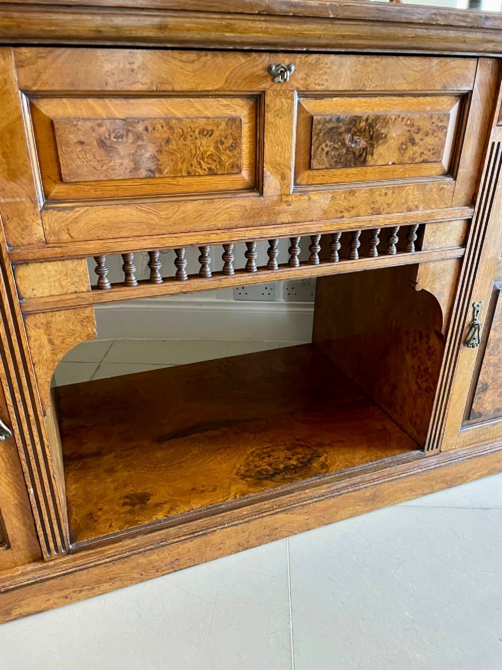 An antique Victorian pollard oak mirror-back sideboard featuring carved field panels, spindled galleries, and multiple mirrored sections. View XII