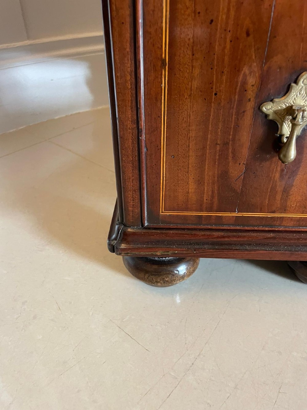 An antique George III walnut kneehole desk featuring crossbanded veneer, brass drop handles, a long frieze drawer, and six pedestal drawers flanking a recessed central cupboard. View II