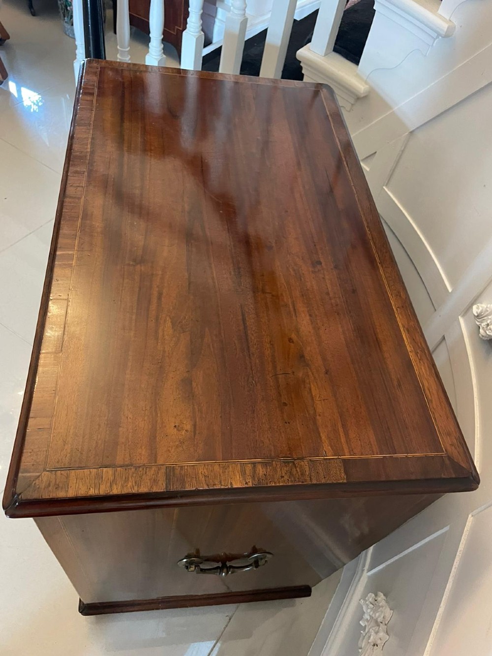 An antique George III walnut kneehole desk featuring crossbanded veneer, brass drop handles, a long frieze drawer, and six pedestal drawers flanking a recessed central cupboard. View VI