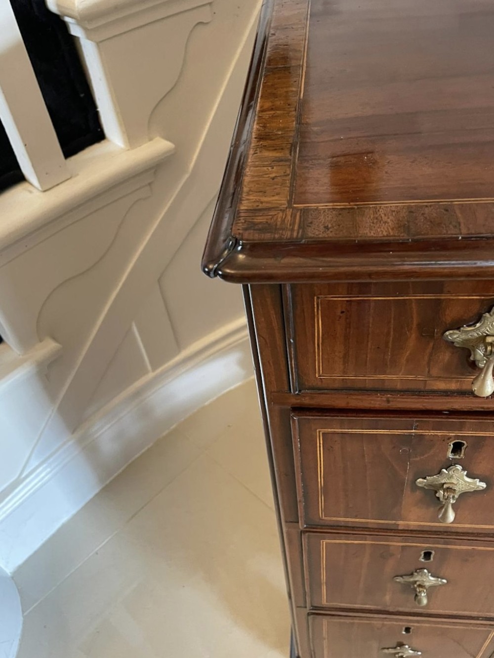 An antique George III walnut kneehole desk featuring crossbanded veneer, brass drop handles, a long frieze drawer, and six pedestal drawers flanking a recessed central cupboard. View XI