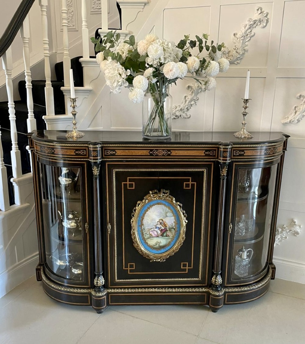 An ebonised nineteenth-century French credenza featuring amboyna wood inlays, gilt-bronze mounts, curved glass door cabinets, and a central painted porcelain plaque. View V