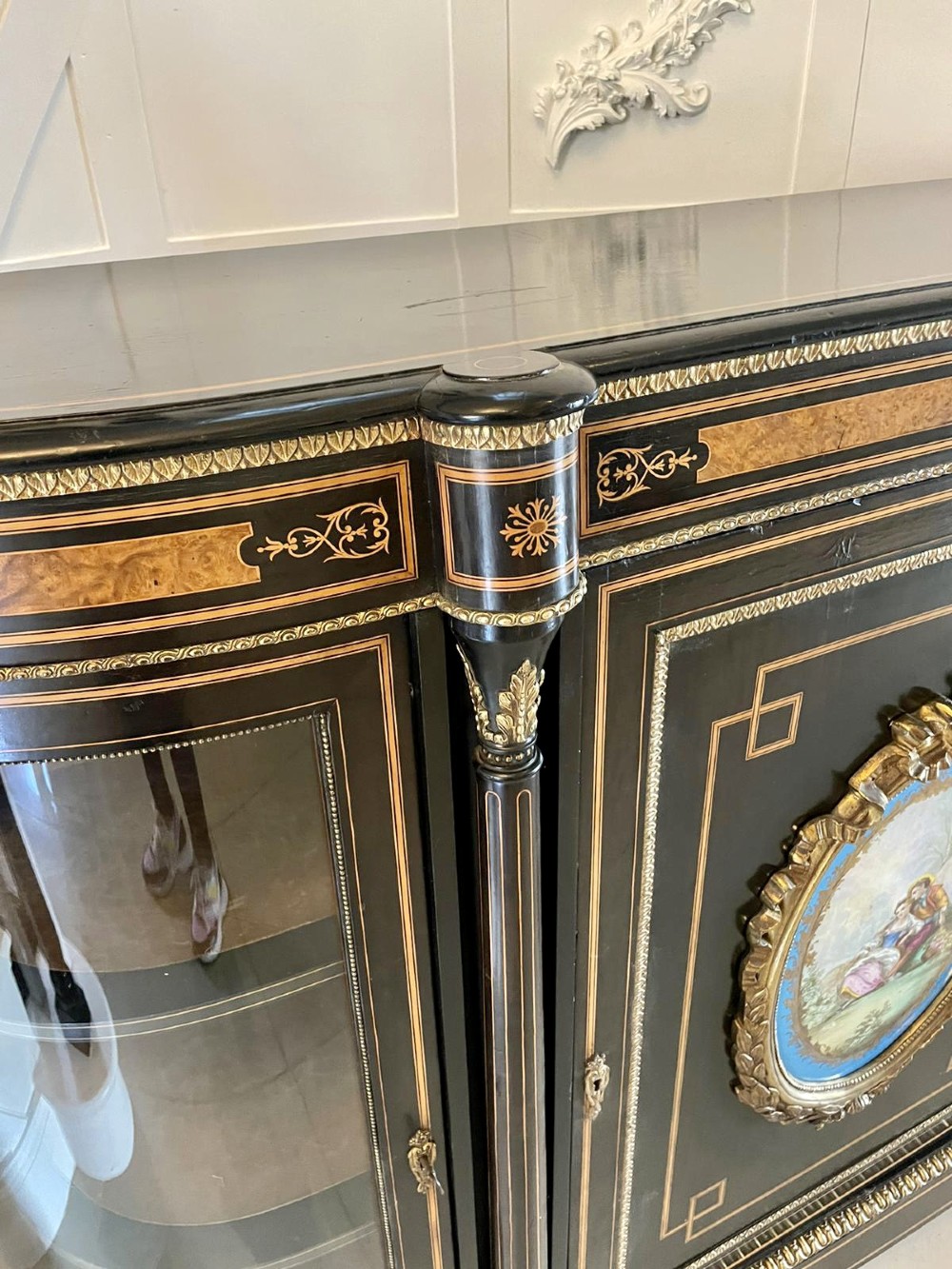 An ebonised nineteenth-century French credenza featuring amboyna wood inlays, gilt-bronze mounts, curved glass door cabinets, and a central painted porcelain plaque. View XI