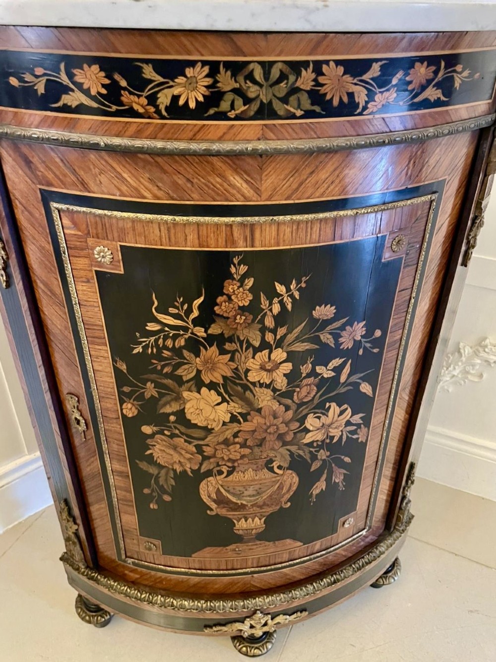 A French Louis XVI style corner cabinet featuring a bow-front door with floral wood marquetry inlay, gilt bronze mounts, and a fitted white marble top. View III