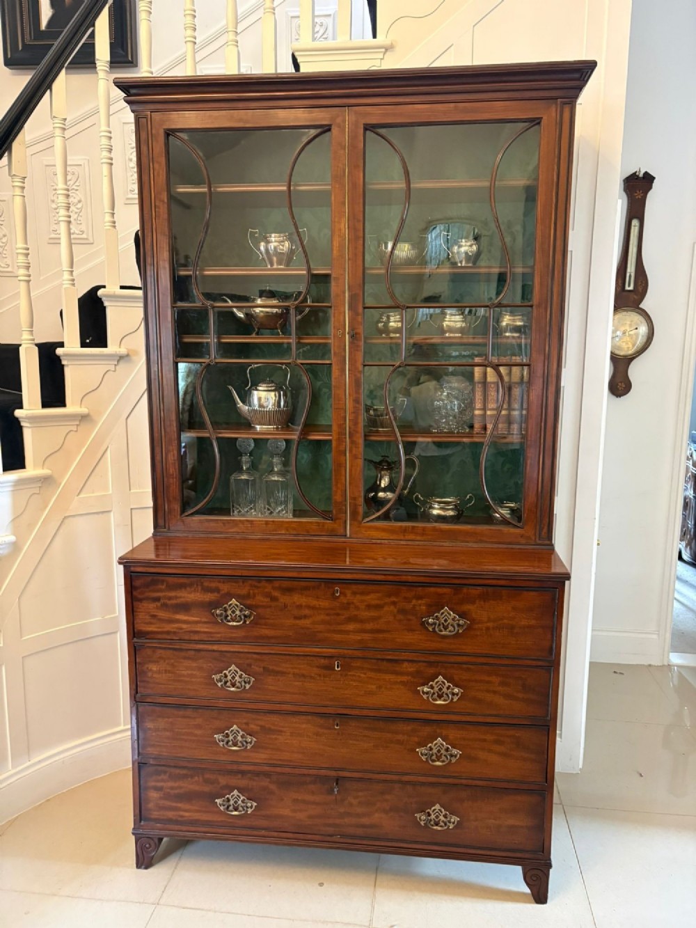 An antique Regency mahogany secretaire bookcase with glazed upper doors featuring curved astragal glazing, resting on a base with four drawers and brass hardware. View II