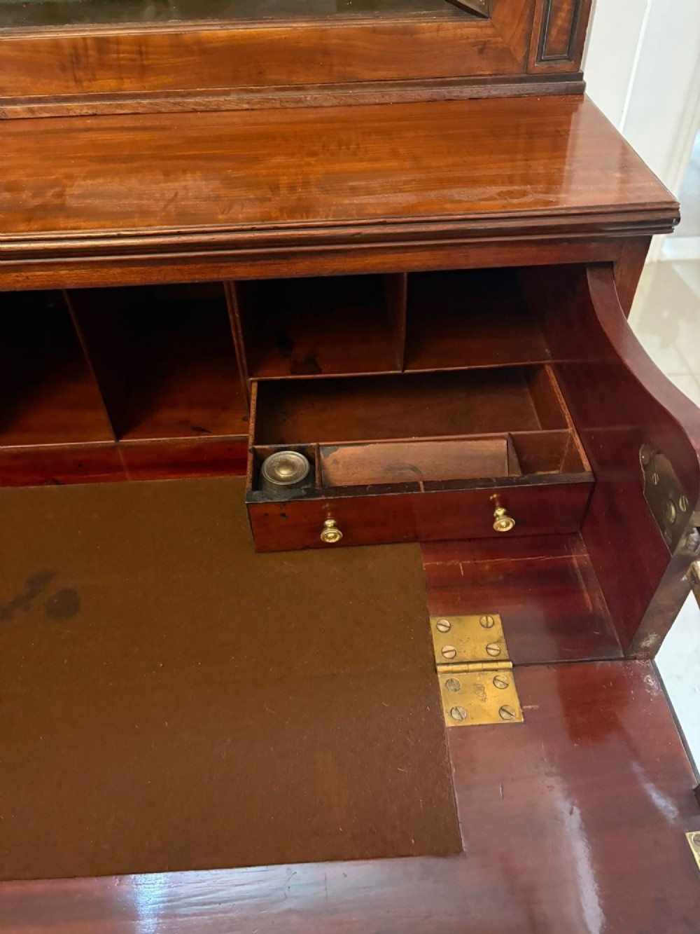 An antique Regency mahogany secretaire bookcase with glazed upper doors featuring curved astragal glazing, resting on a base with four drawers and brass hardware. View IV