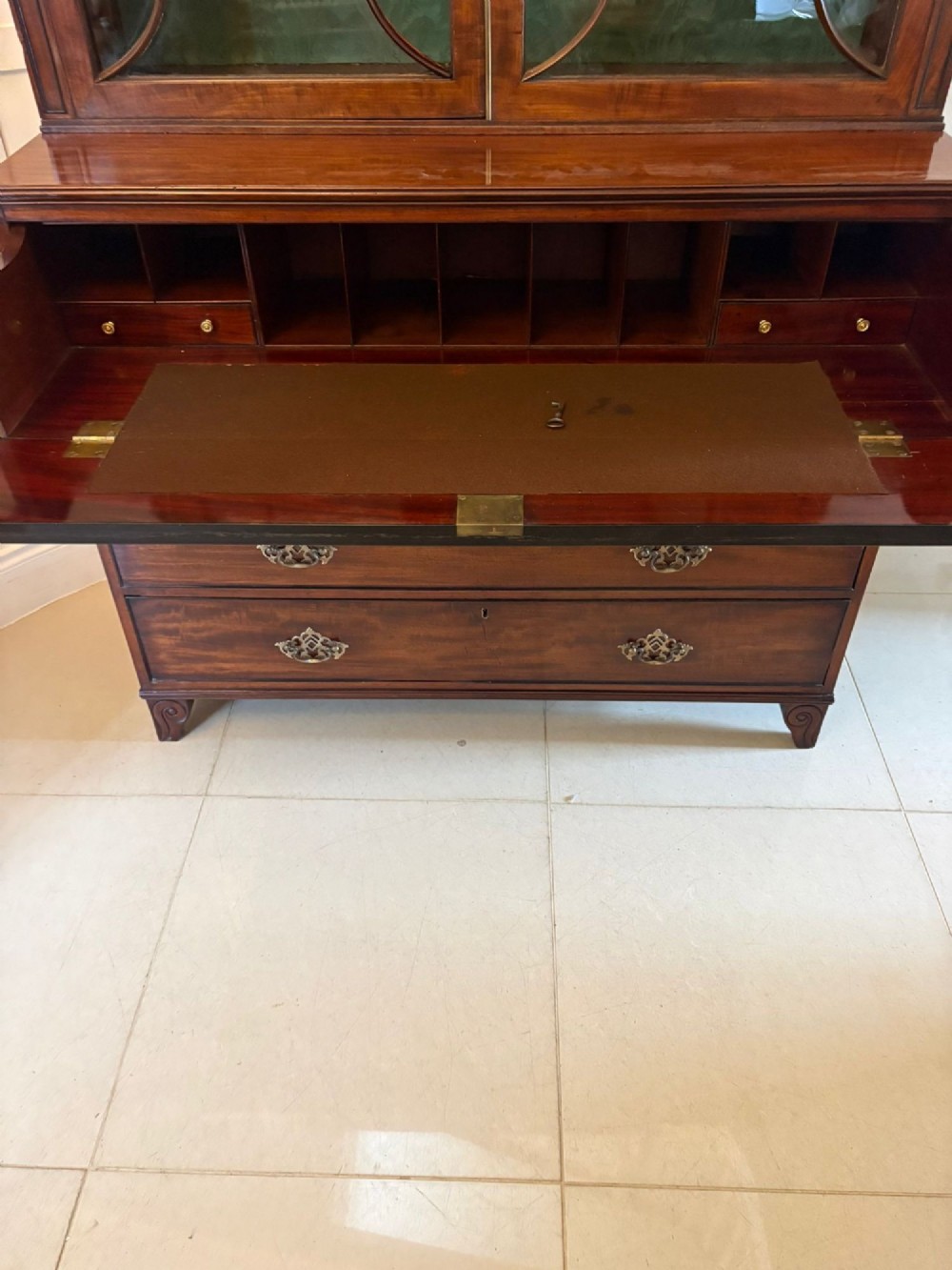 An antique Regency mahogany secretaire bookcase with glazed upper doors featuring curved astragal glazing, resting on a base with four drawers and brass hardware. View VIII