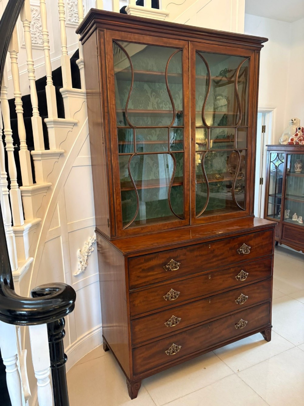 An antique Regency mahogany secretaire bookcase with glazed upper doors featuring curved astragal glazing, resting on a base with four drawers and brass hardware. View XII