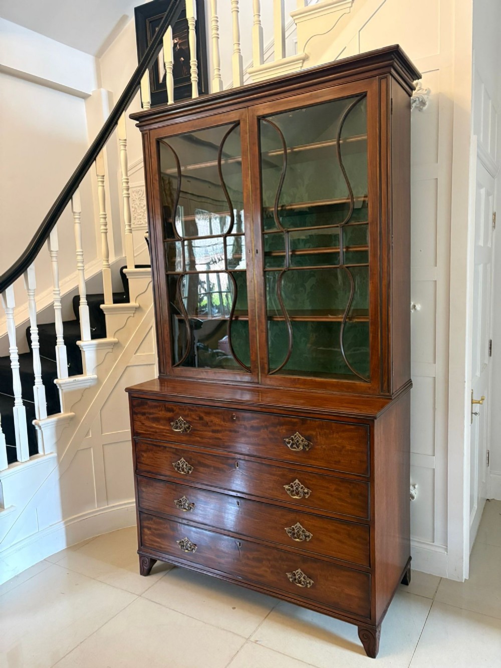 An antique Regency mahogany secretaire bookcase with glazed upper doors featuring curved astragal glazing, resting on a base with four drawers and brass hardware. View XIV