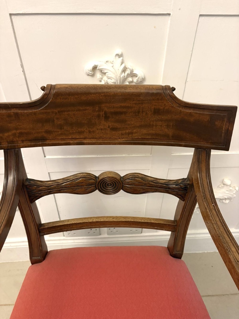 A set of twelve Regency mahogany dining chairs featuring tablet top back rails, carved crossbars, and terracotta fabric upholstered seats, including two carvers with curved armrests. View V