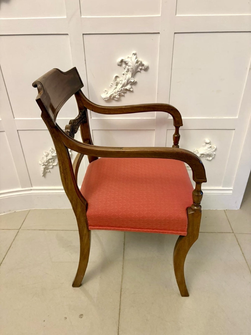 A set of twelve Regency mahogany dining chairs featuring tablet top back rails, carved crossbars, and terracotta fabric upholstered seats, including two carvers with curved armrests. View VI
