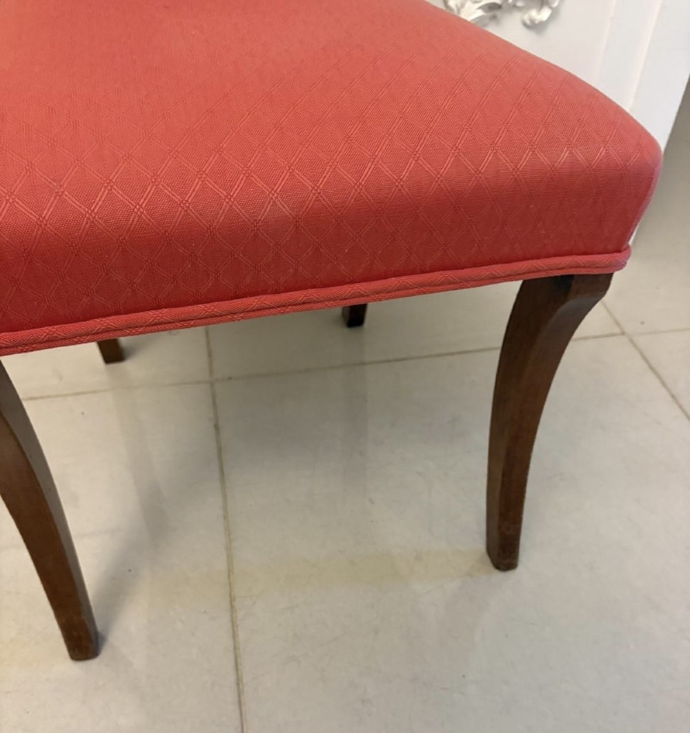 A set of twelve Regency mahogany dining chairs featuring tablet top back rails, carved crossbars, and terracotta fabric upholstered seats, including two carvers with curved armrests. View X