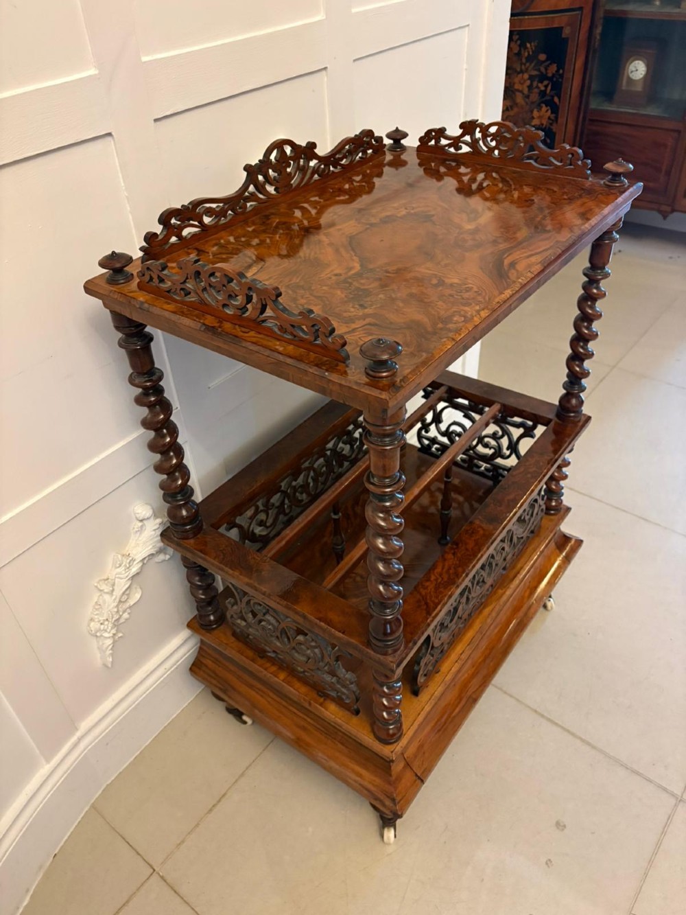 A Victorian burr walnut Canterbury featuring a top surface with a pierced fretwork gallery, barley twist supports, divided slots, and a single drawer resting on porcelain castors. View VIII