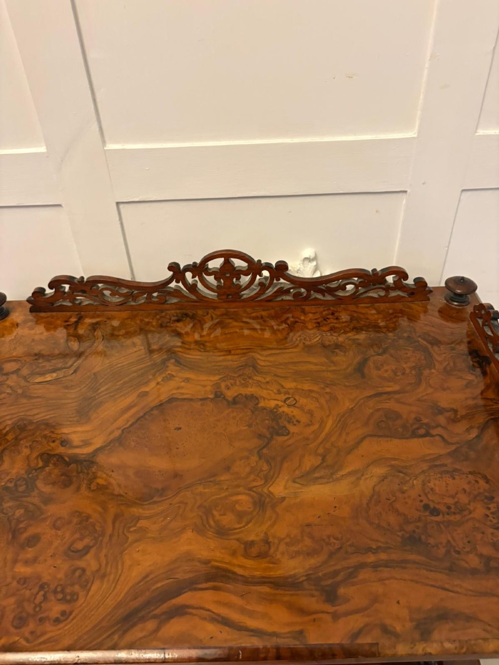 A Victorian burr walnut Canterbury featuring a top surface with a pierced fretwork gallery, barley twist supports, divided slots, and a single drawer resting on porcelain castors. View IX