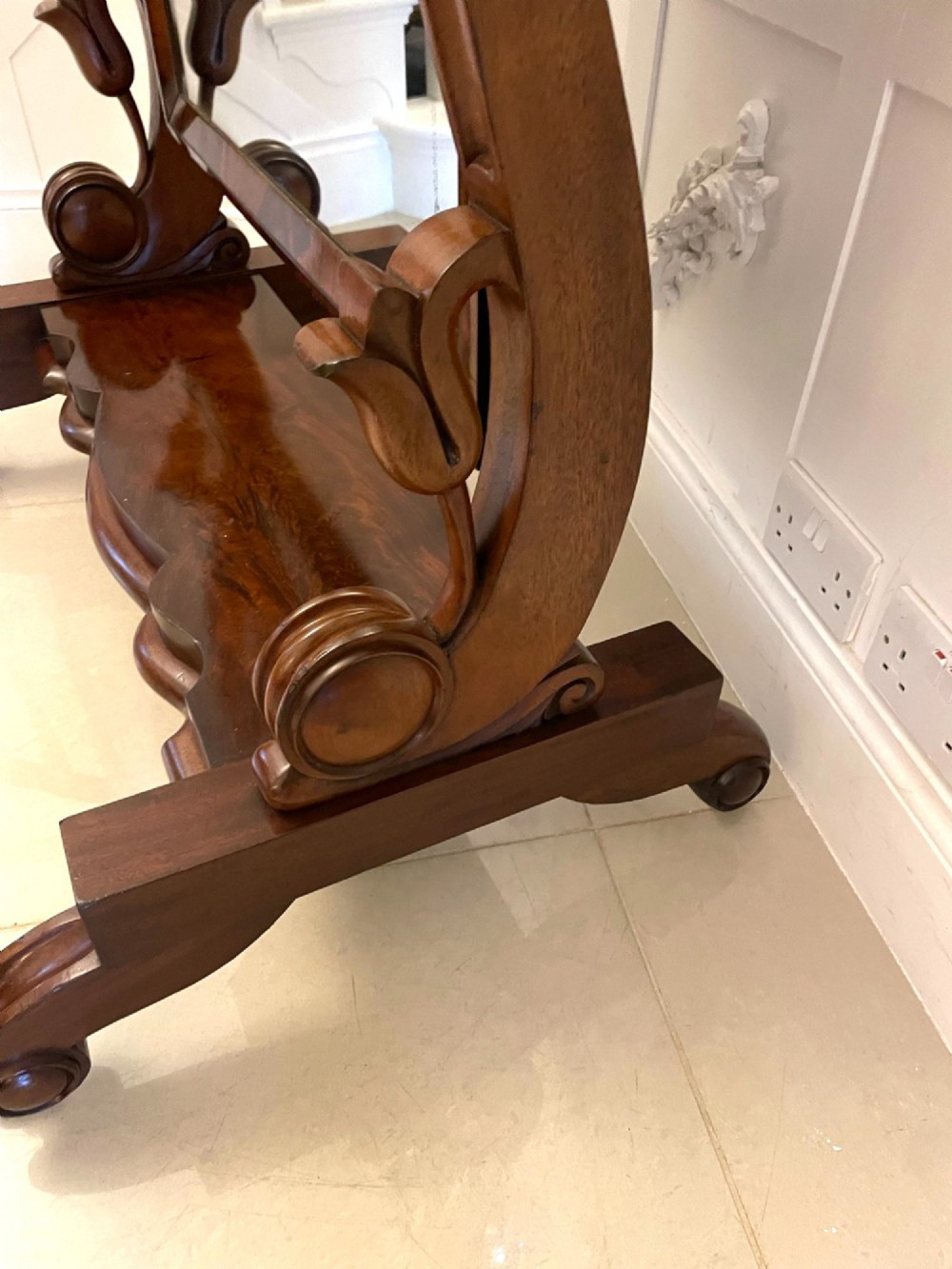 A full-length Victorian mahogany cheval mirror featuring a rounded rectangular swivelling frame, carved scroll uprights, a shaped plinth base, and brass castors. View III