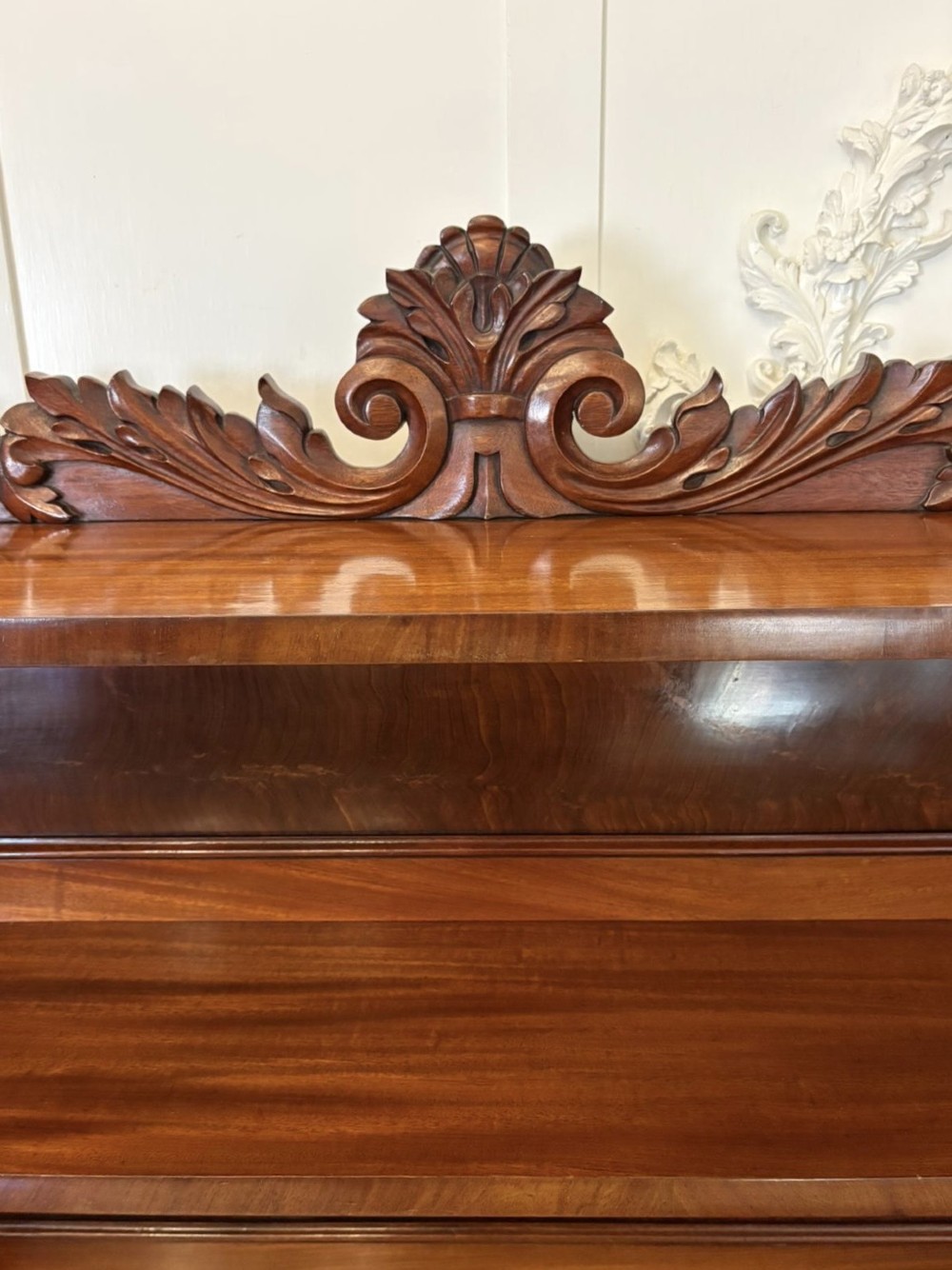 A Victorian mahogany chiffonier featuring a two-tiered upper shelf superstructure with carved scroll supports and a lower cupboard with flame mahogany veneered doors. View VI