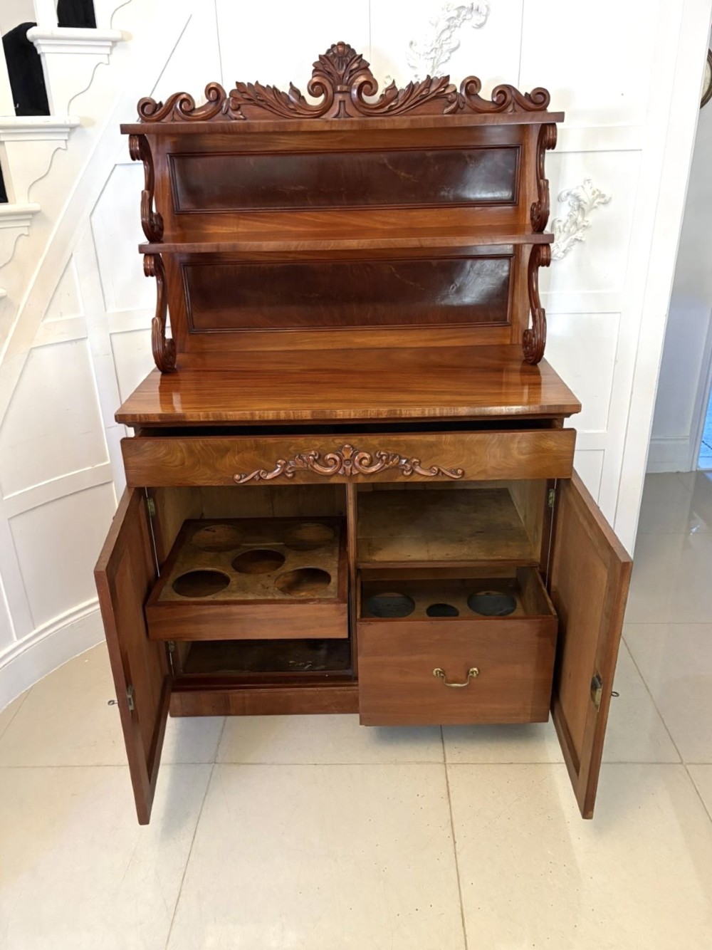 A Victorian mahogany chiffonier featuring a two-tiered upper shelf superstructure with carved scroll supports and a lower cupboard with flame mahogany veneered doors. View VIII