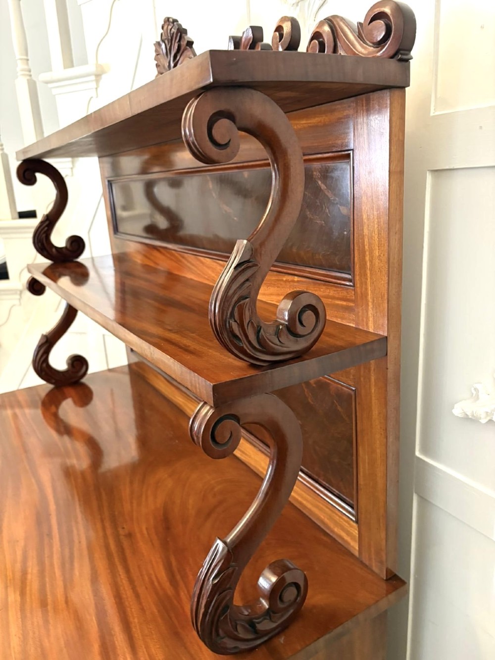 A Victorian mahogany chiffonier featuring a two-tiered upper shelf superstructure with carved scroll supports and a lower cupboard with flame mahogany veneered doors. View IX