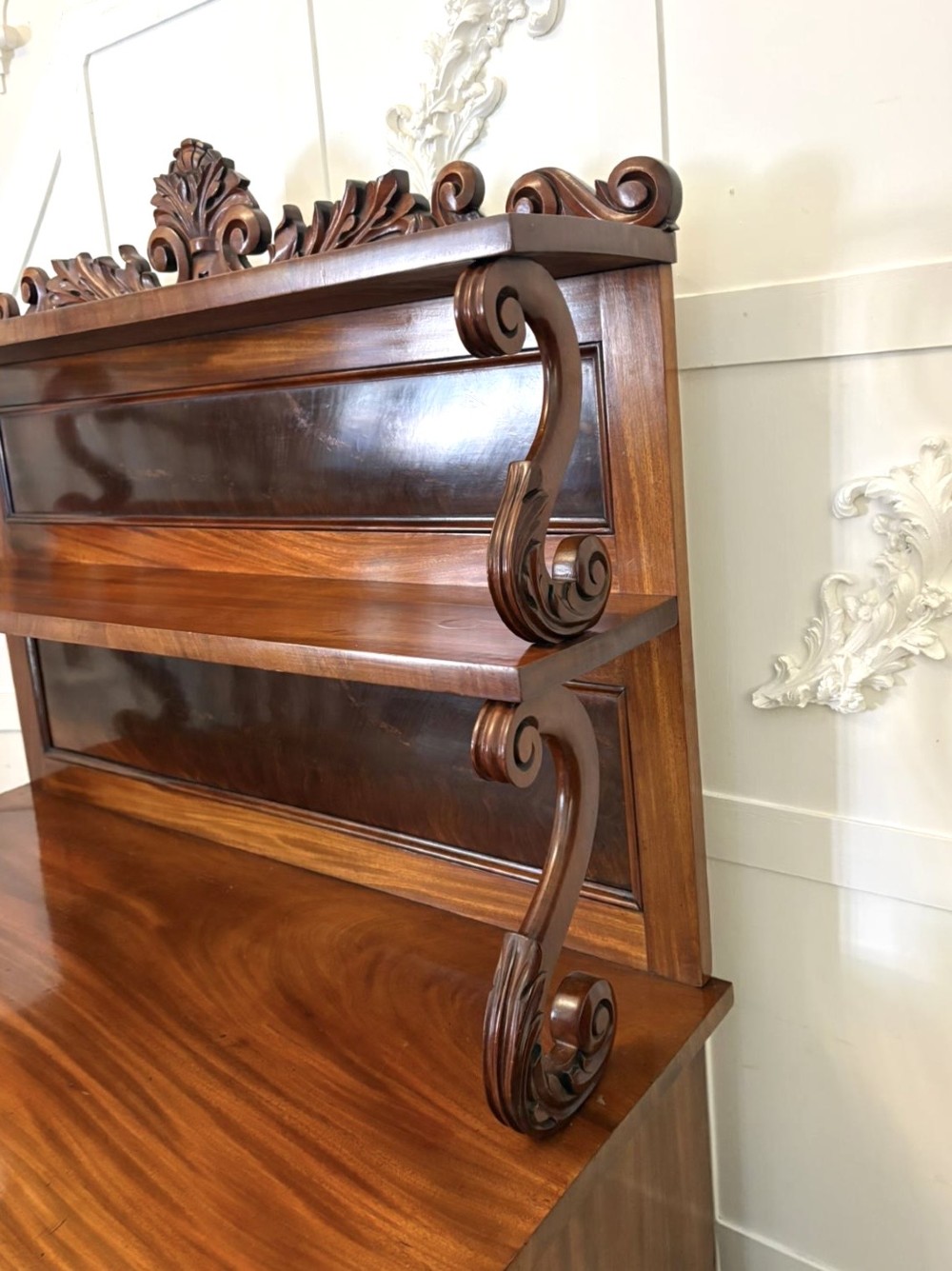A Victorian mahogany chiffonier featuring a two-tiered upper shelf superstructure with carved scroll supports and a lower cupboard with flame mahogany veneered doors. View XI