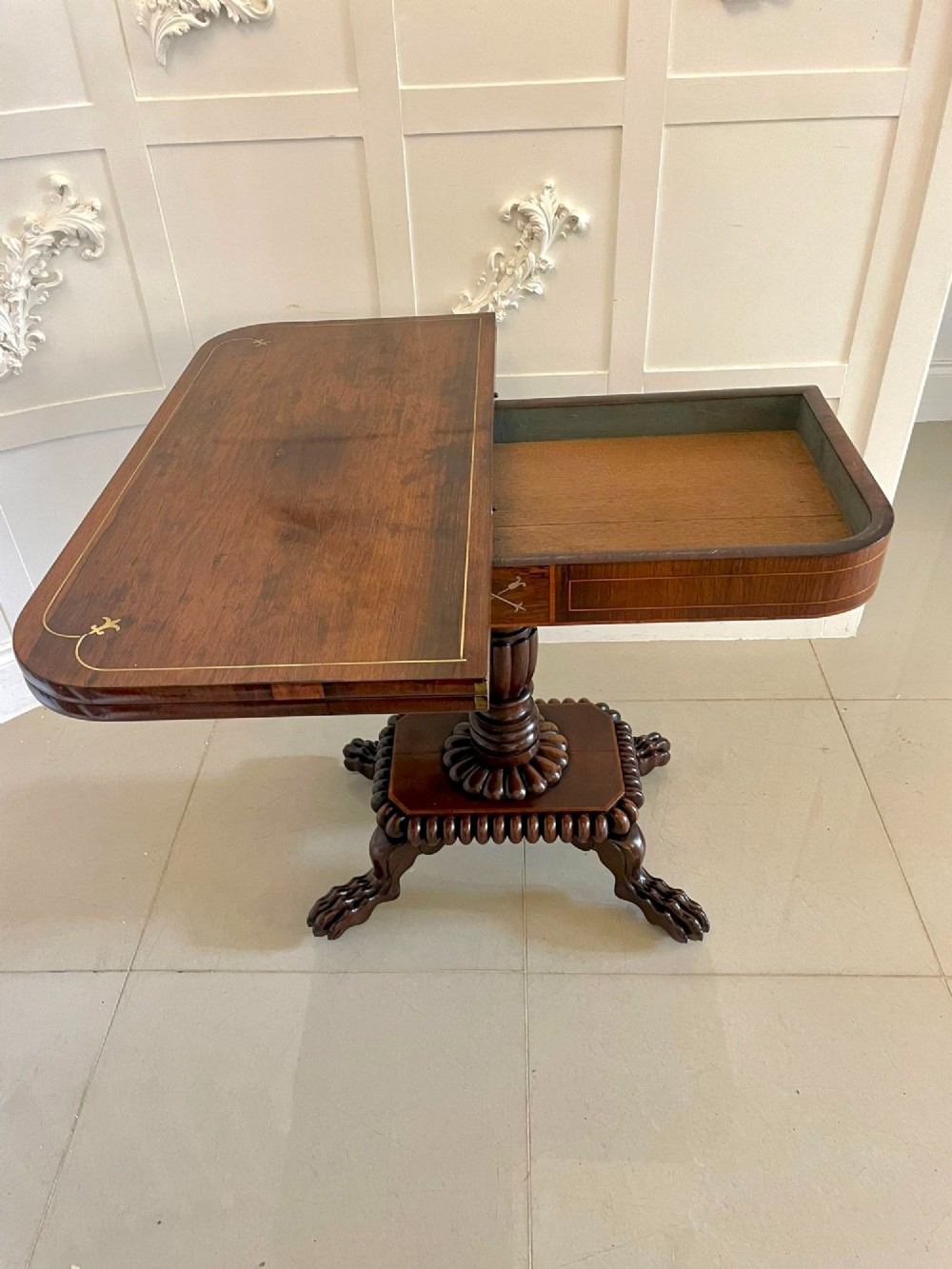 A Regency fold-over rosewood card table with brass inlay, a central pedestal, and carved lion paw feet. View IV