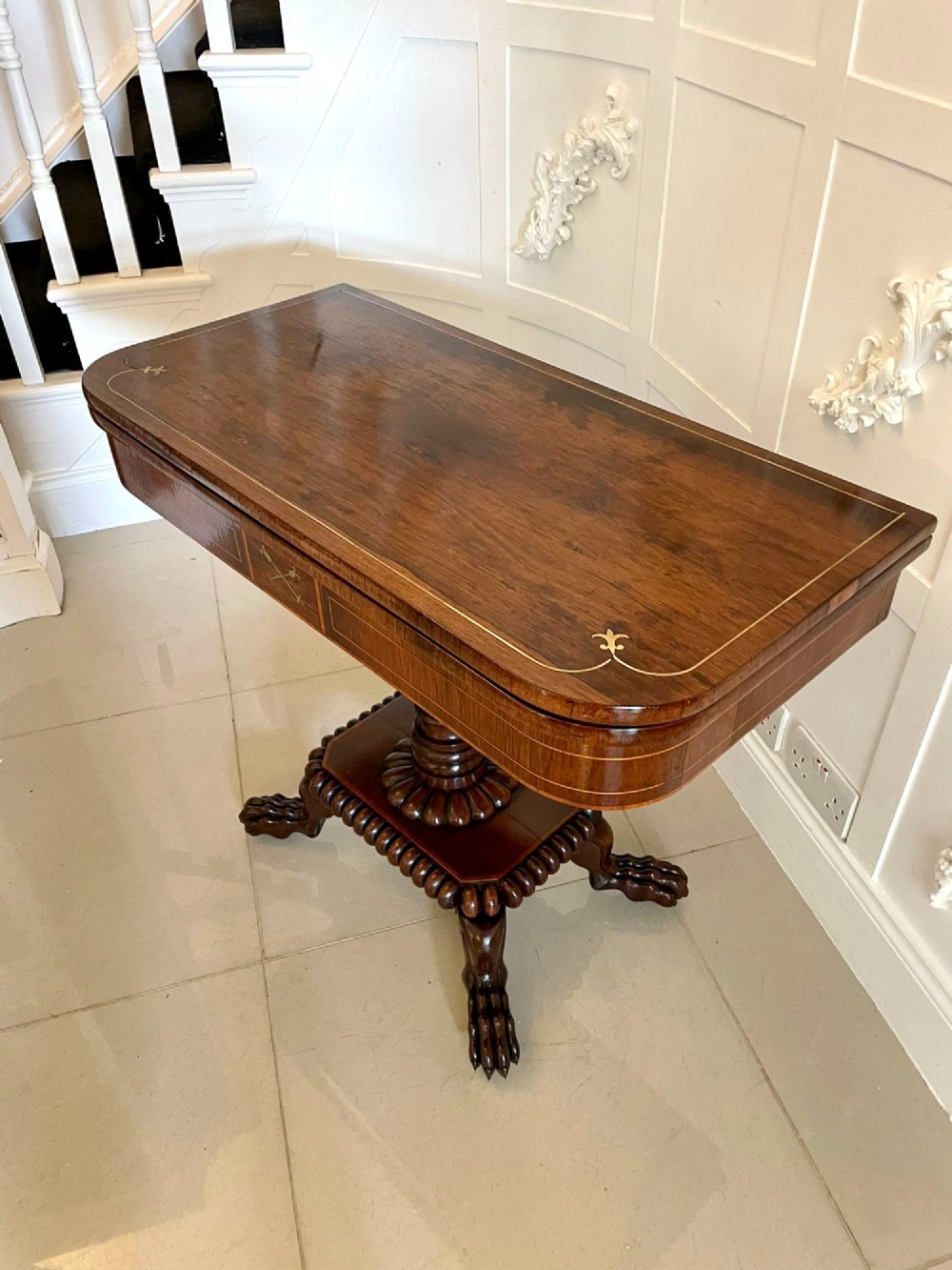 A Regency fold-over rosewood card table with brass inlay, a central pedestal, and carved lion paw feet. View VI