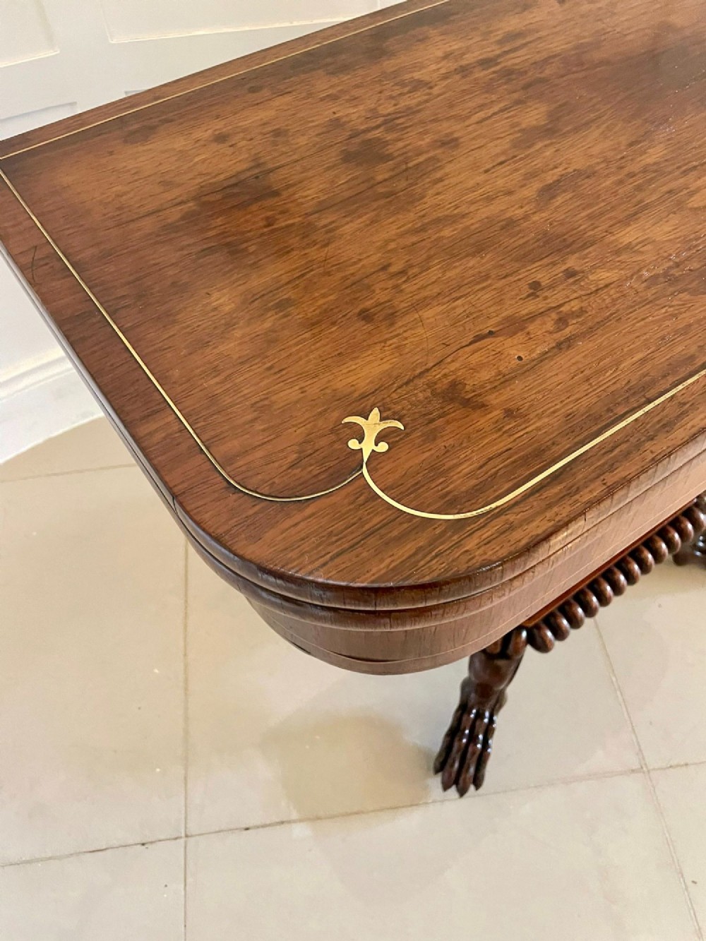 A Regency fold-over rosewood card table with brass inlay, a central pedestal, and carved lion paw feet. View XI