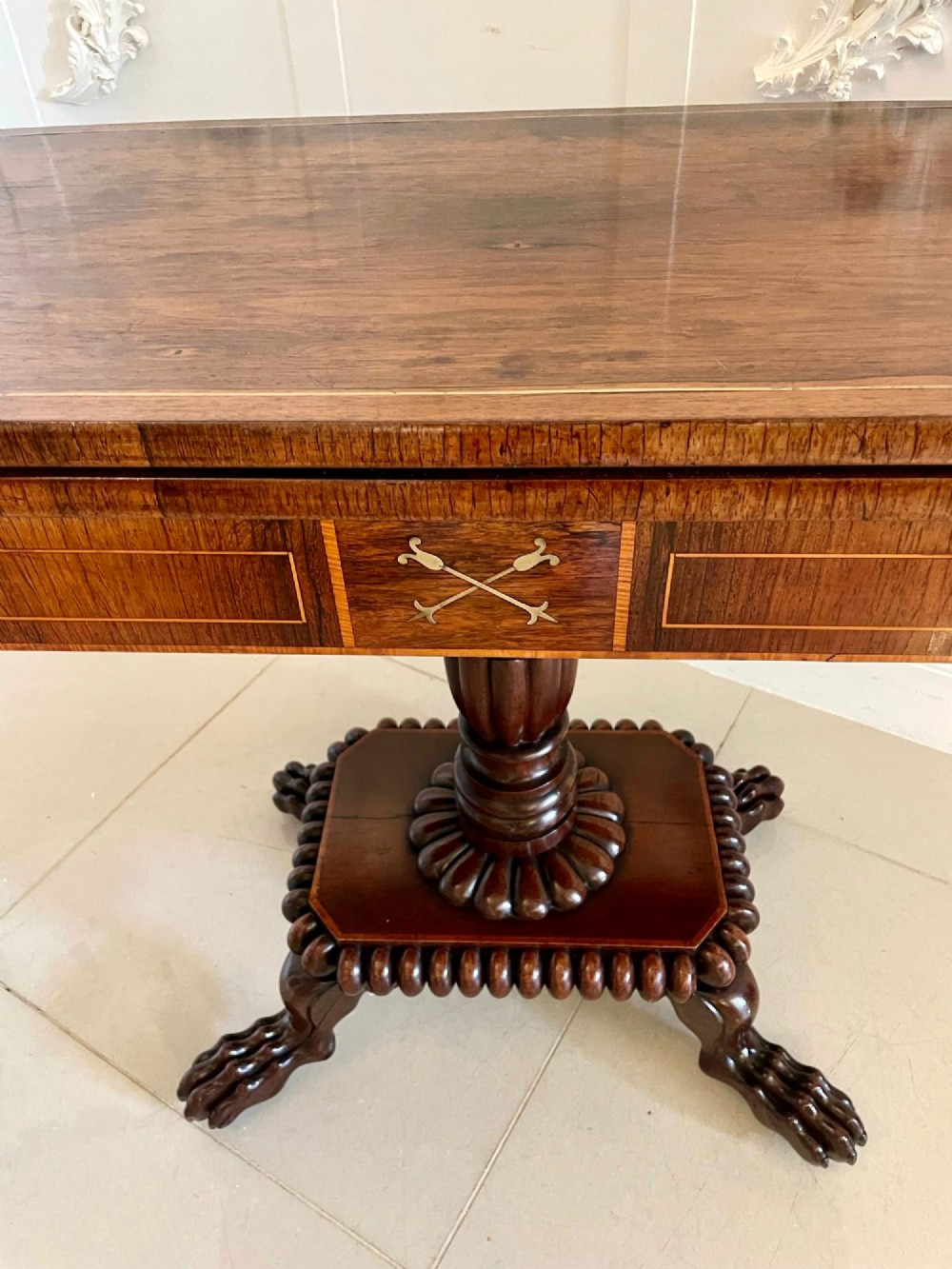 A Regency fold-over rosewood card table with brass inlay, a central pedestal, and carved lion paw feet. View XII