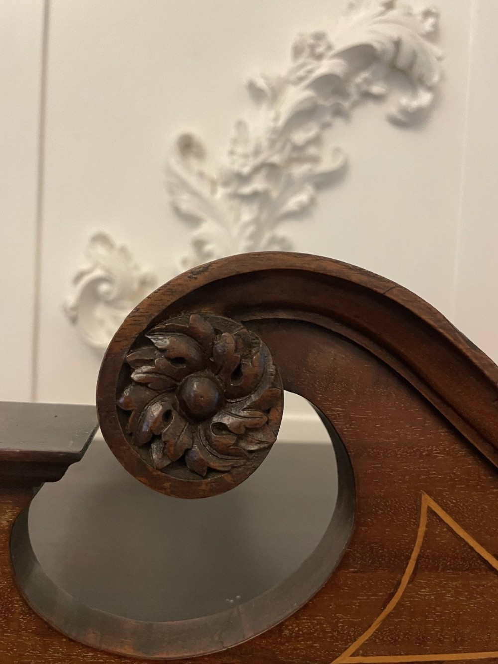 An antique mahogany display cabinet featuring a swan neck pediment, marquetry inlays, glazed double doors, interior glass shelves, and square tapered legs. View V