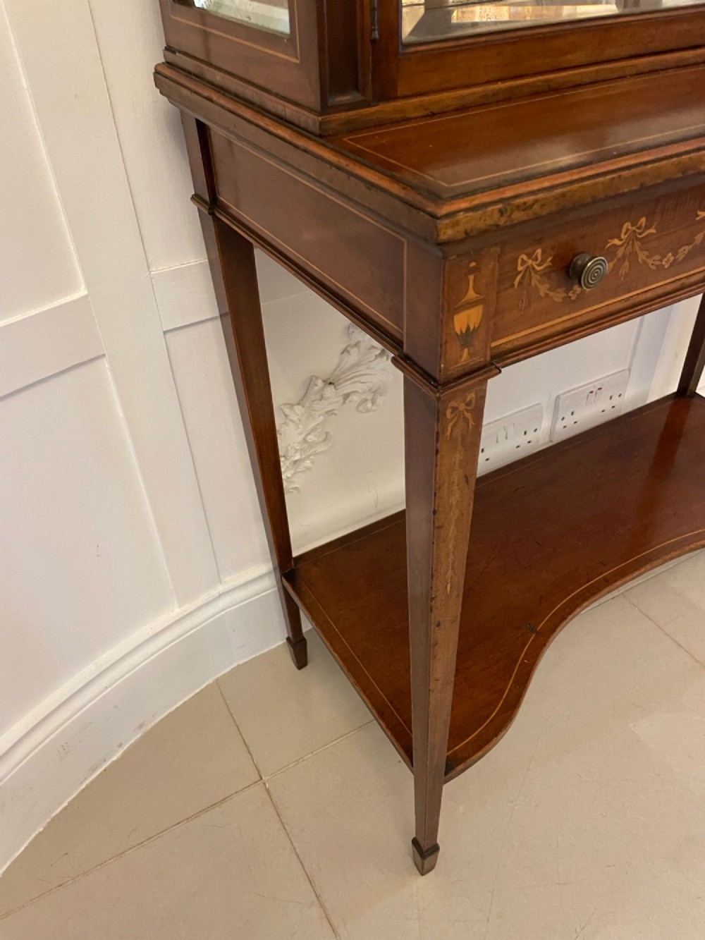 An antique mahogany display cabinet featuring a swan neck pediment, marquetry inlays, glazed double doors, interior glass shelves, and square tapered legs. View VIII