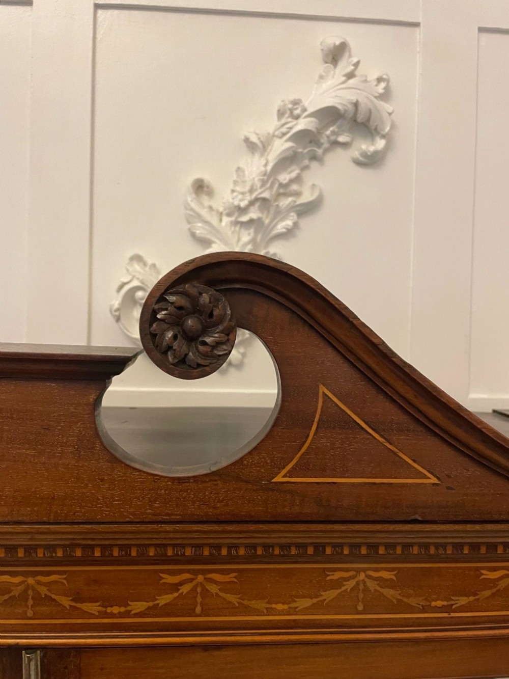 An antique mahogany display cabinet featuring a swan neck pediment, marquetry inlays, glazed double doors, interior glass shelves, and square tapered legs. View IX