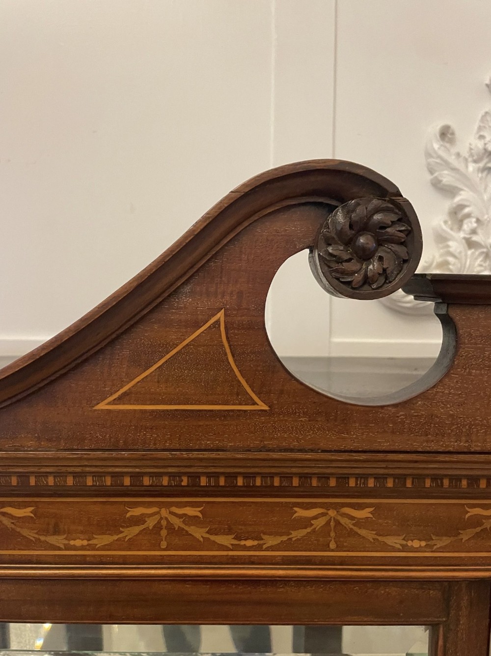 An antique mahogany display cabinet featuring a swan neck pediment, marquetry inlays, glazed double doors, interior glass shelves, and square tapered legs. View XII