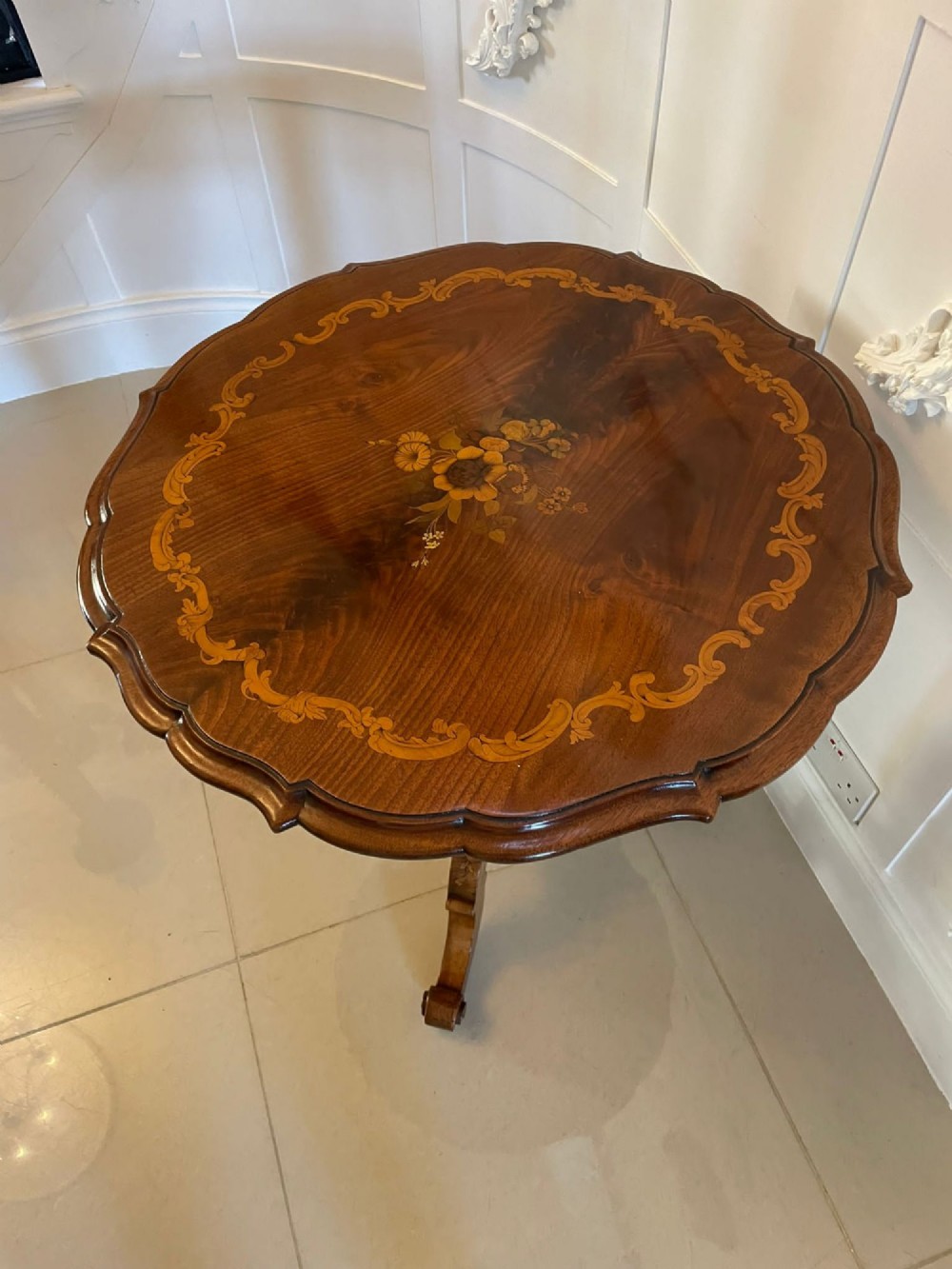 A Victorian walnut occasional table featuring a scalloped rim, intricate marquetry floral inlay on the tabletop, a turned central pedestal, and three carved cabriole legs. View IV
