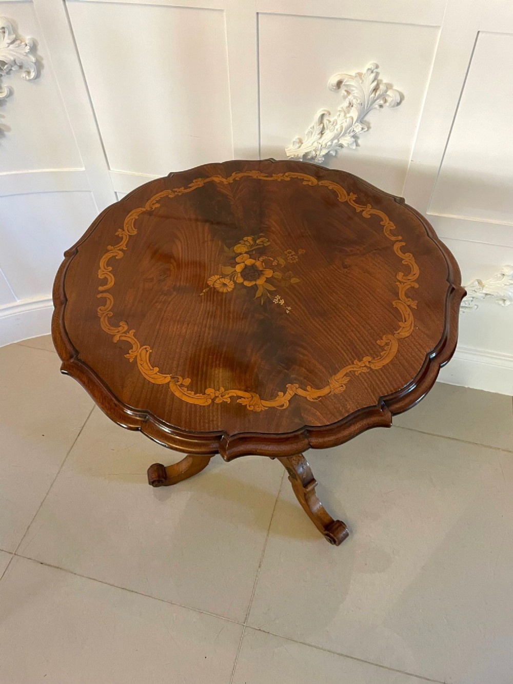 A Victorian walnut occasional table featuring a scalloped rim, intricate marquetry floral inlay on the tabletop, a turned central pedestal, and three carved cabriole legs. View XIV