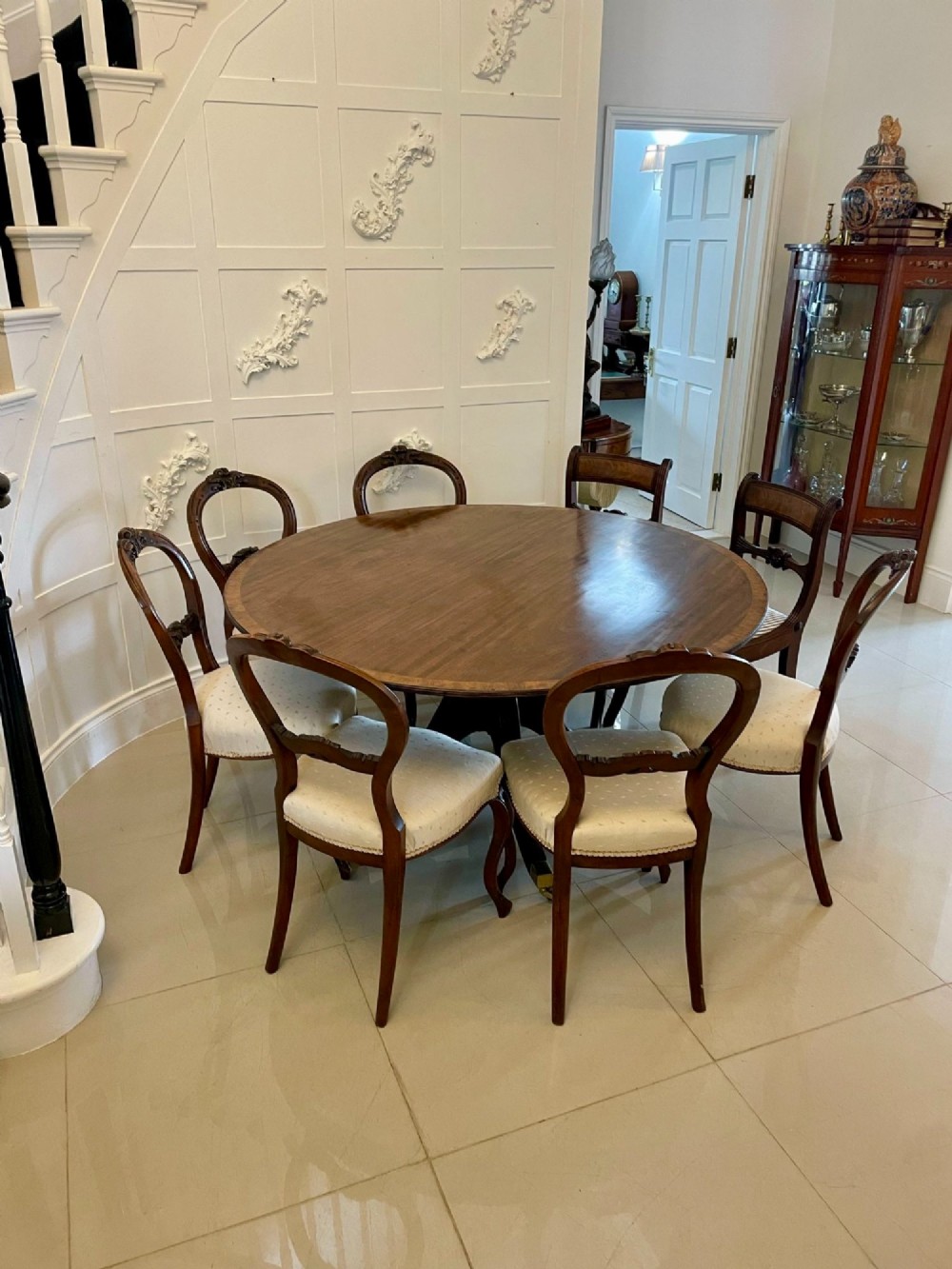 A circular George III figured mahogany tilt-top dining table positioned vertically on a four-legged pedestal base with brass castors. View III