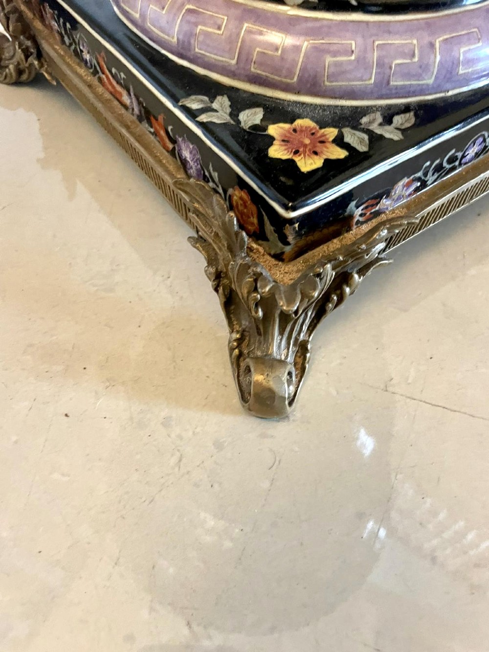 A pair of black French porcelain jardiniere urns featuring polychrome floral enamel, central painted animal reserves, and gadrooned brass mounts on square plinths. View V