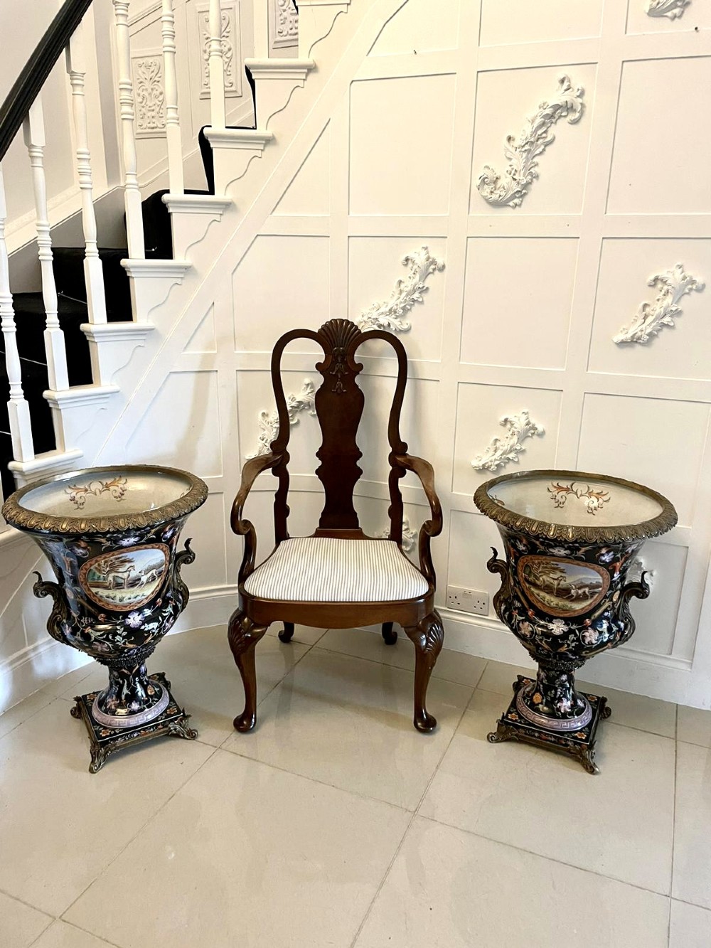 A pair of black French porcelain jardiniere urns featuring polychrome floral enamel, central painted animal reserves, and gadrooned brass mounts on square plinths. View VI