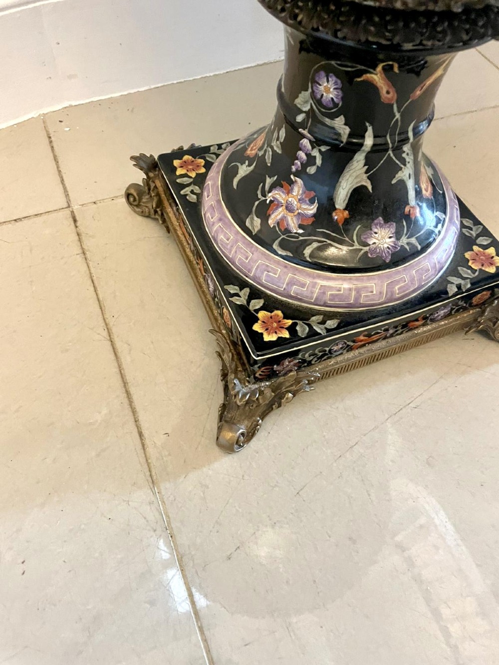 A pair of black French porcelain jardiniere urns featuring polychrome floral enamel, central painted animal reserves, and gadrooned brass mounts on square plinths. View X