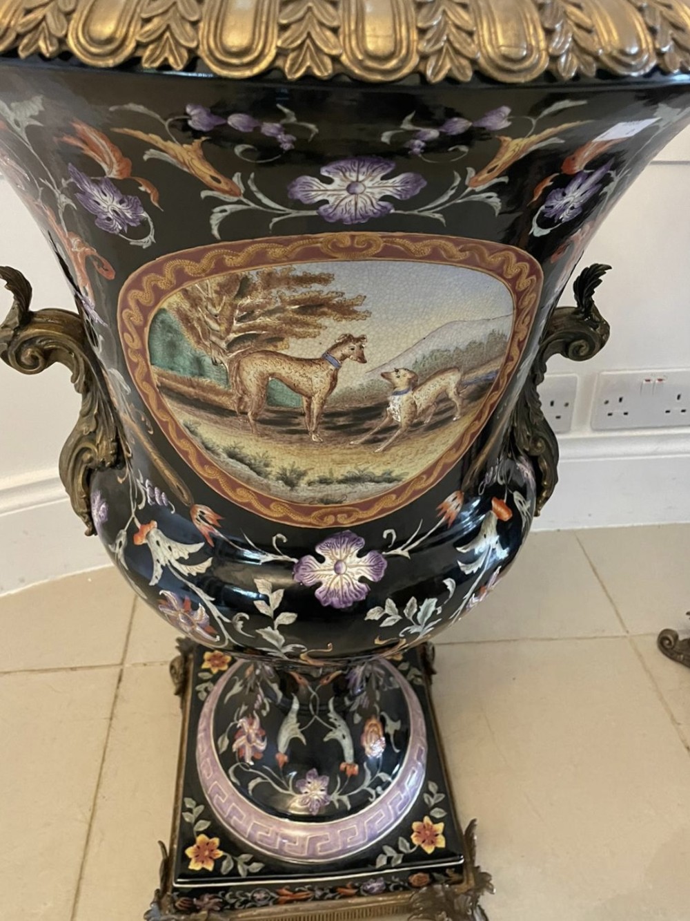 A pair of black French porcelain jardiniere urns featuring polychrome floral enamel, central painted animal reserves, and gadrooned brass mounts on square plinths. View XII