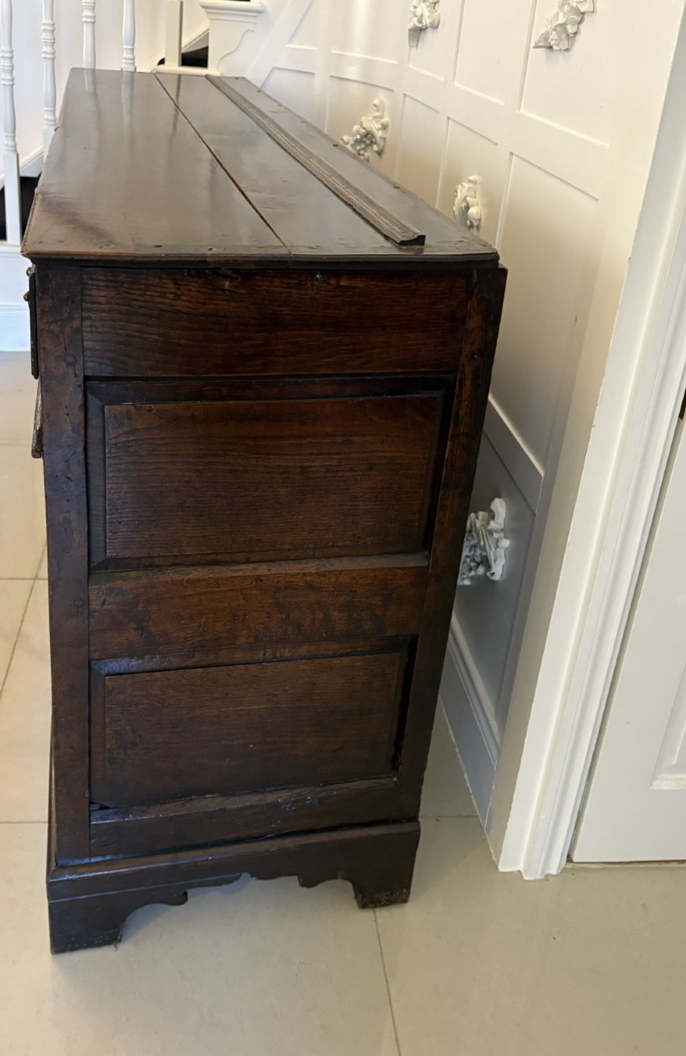 A George III dark oak dresser base featuring multiple drawers, arched cupboard doors, and brass swan-neck handles. View X
