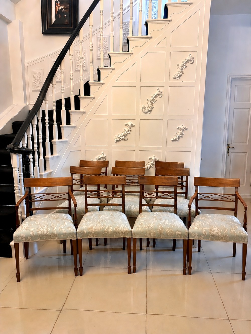 A set of ten Edwardian mahogany dining chairs, including two carver armchairs, featuring lattice backrests and pale blue patterned fabric upholstery.