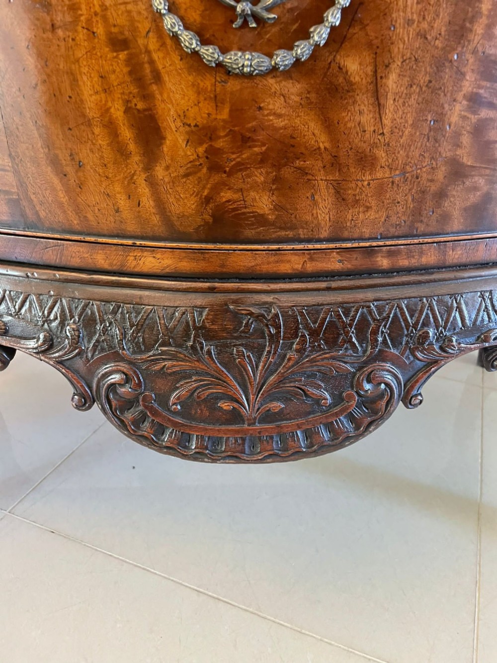 A Victorian figured mahogany serpentine chest of drawers featuring two drawers with cast brass handles, a deeply carved apron, and cabriole legs. View II