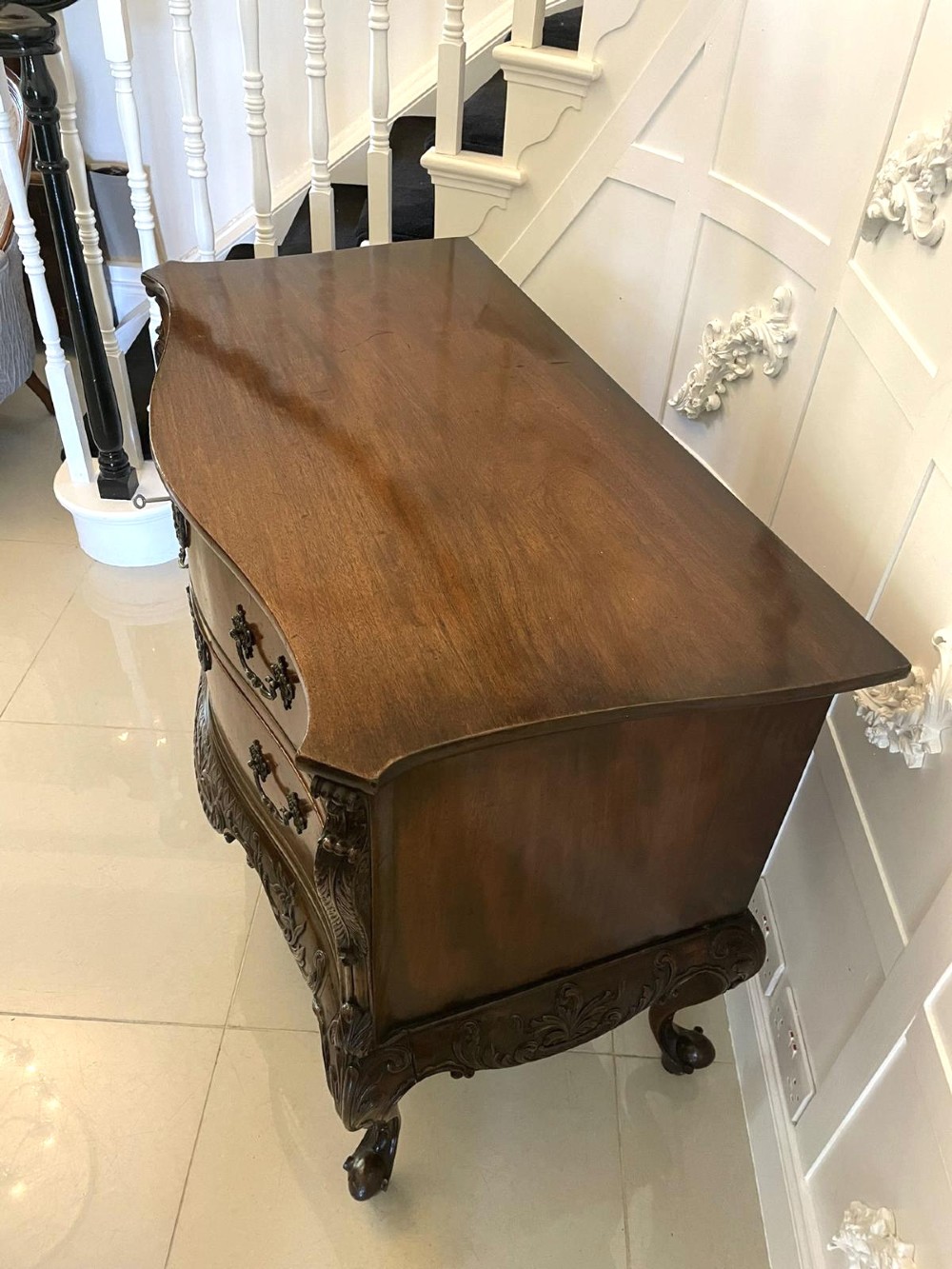 A Victorian figured mahogany serpentine chest of drawers featuring two drawers with cast brass handles, a deeply carved apron, and cabriole legs. View XIII