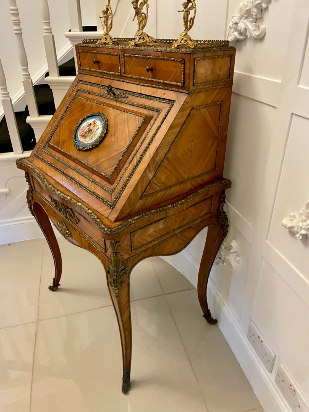 A French Rococo revival slant-front kingwood bureau featuring delicate ormolu mounts, a central hand-painted porcelain plaque, and elegant cabriole legs. View III