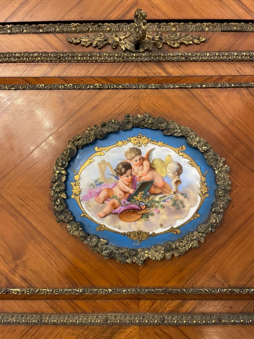 A French Rococo revival slant-front kingwood bureau featuring delicate ormolu mounts, a central hand-painted porcelain plaque, and elegant cabriole legs. View IV