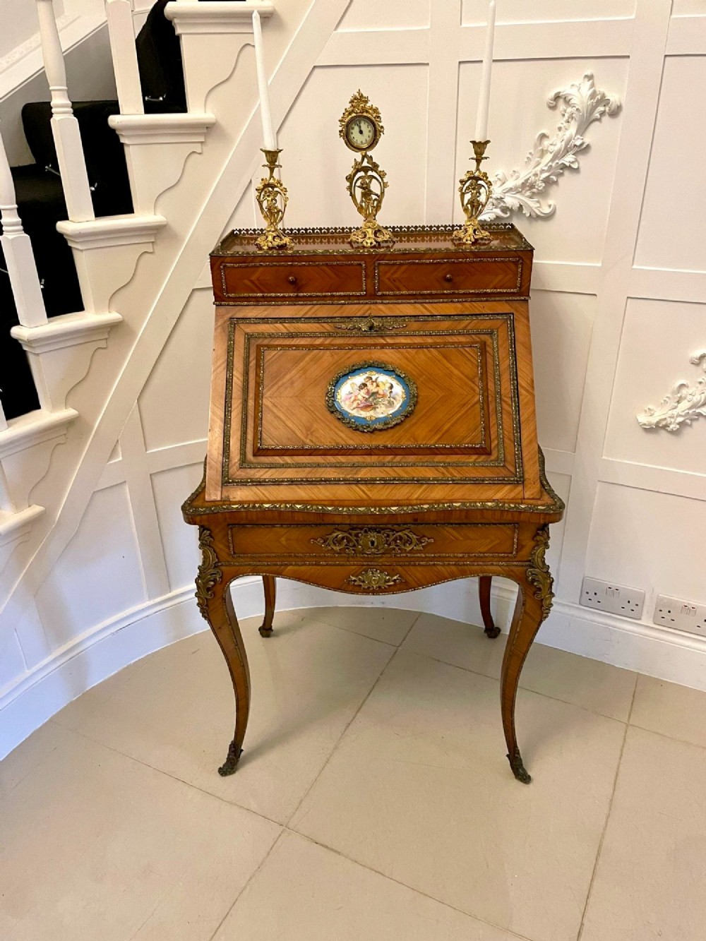 A French Rococo revival slant-front kingwood bureau featuring delicate ormolu mounts, a central hand-painted porcelain plaque, and elegant cabriole legs. View X