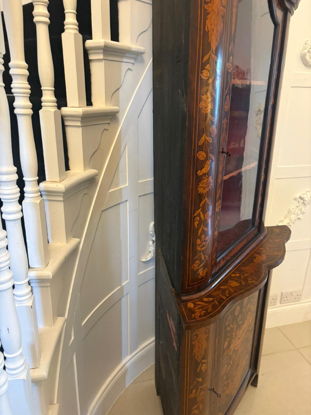 A 19th-century two-tier Dutch marquetry corner cabinet featuring intricate floral inlays, an arched glazed top door, and a solid lower cupboard door. View VI