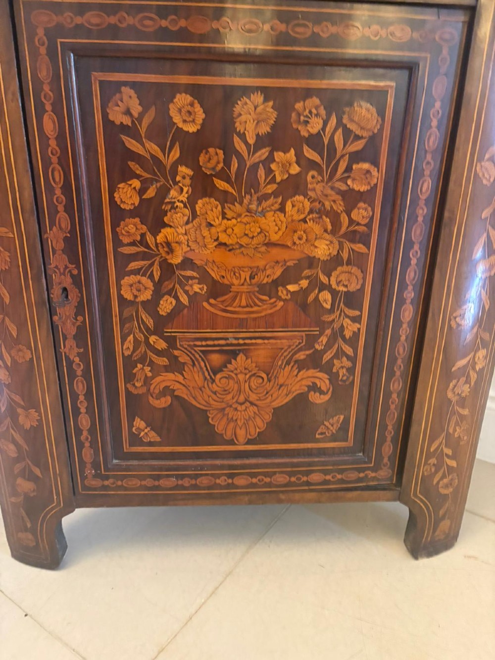 A 19th-century two-tier Dutch marquetry corner cabinet featuring intricate floral inlays, an arched glazed top door, and a solid lower cupboard door. View VIII