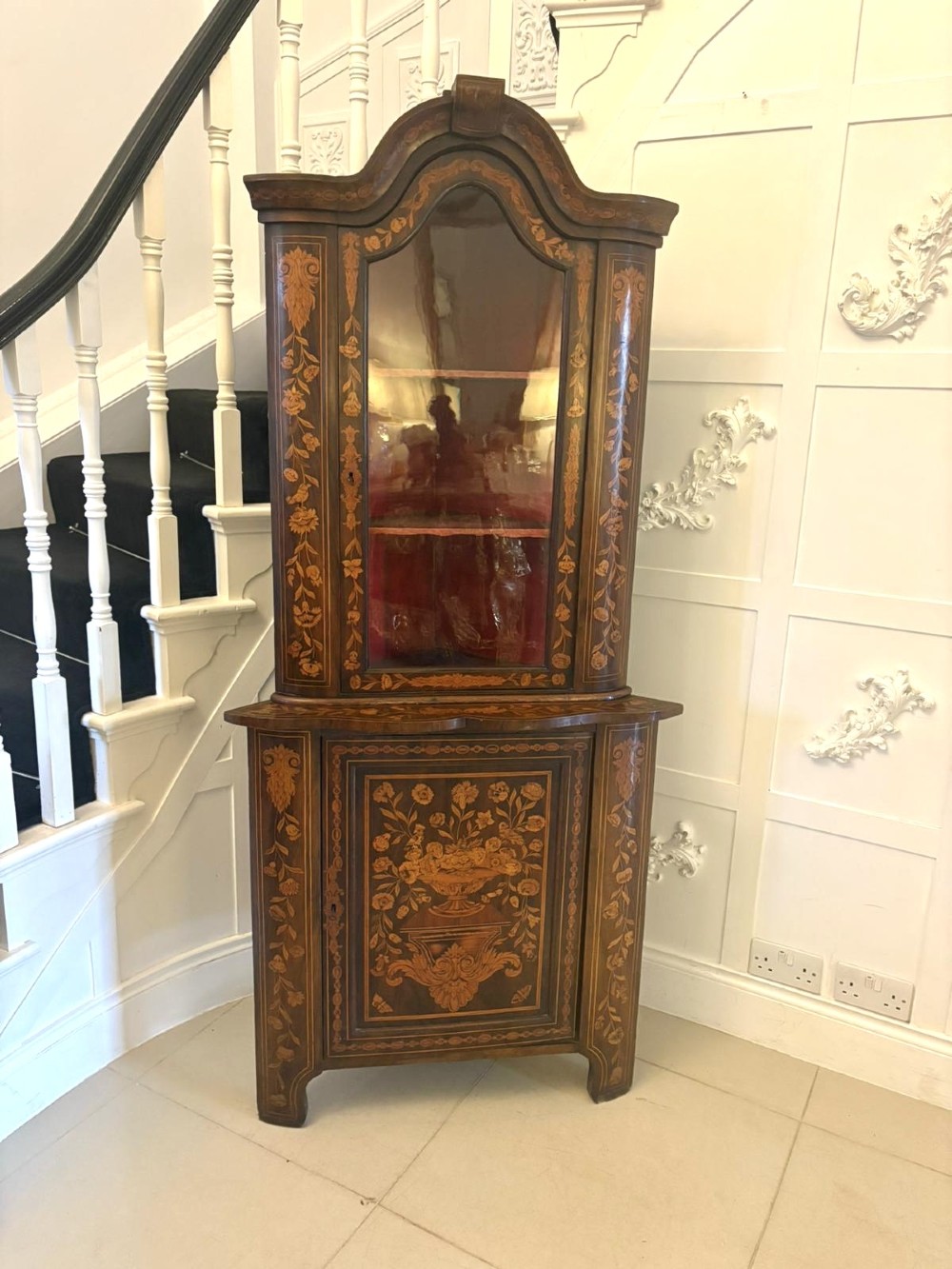 A 19th-century two-tier Dutch marquetry corner cabinet featuring intricate floral inlays, an arched glazed top door, and a solid lower cupboard door. View XII