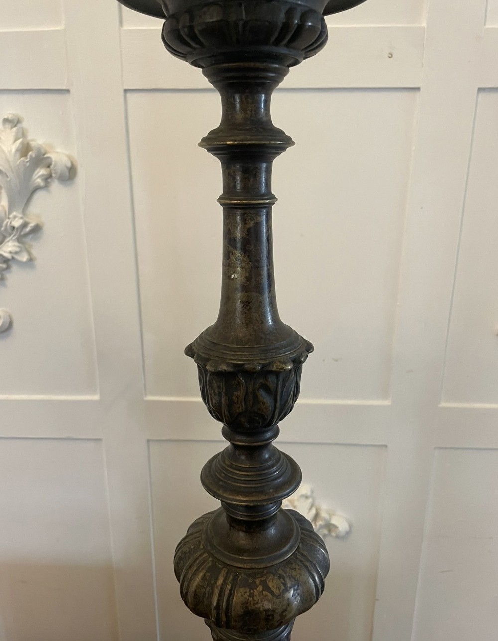 A pair of tall antique Victorian brass pricket candlesticks featuring ornate baluster shafts, foliate details, and spiked drip pans resting on decorative tripod bases. View II